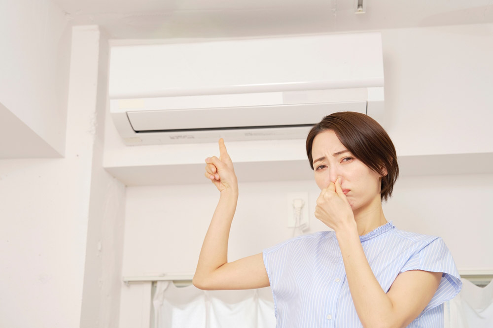 person holding their nose near AC